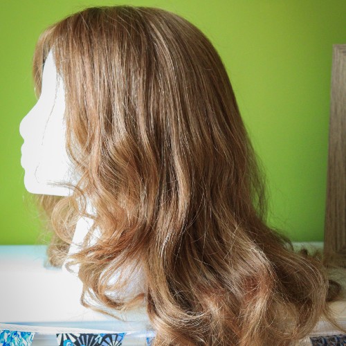 A mannequin head with a long brown curly wig