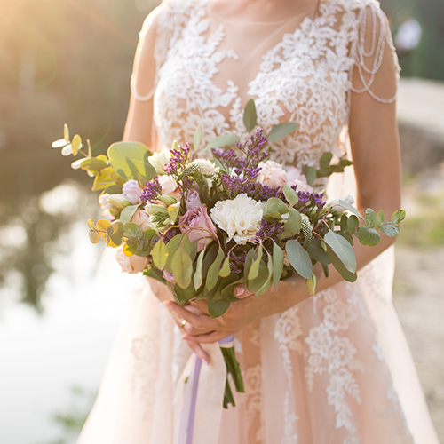 A woman in a wedding dress, holding a beautiful bouquet.