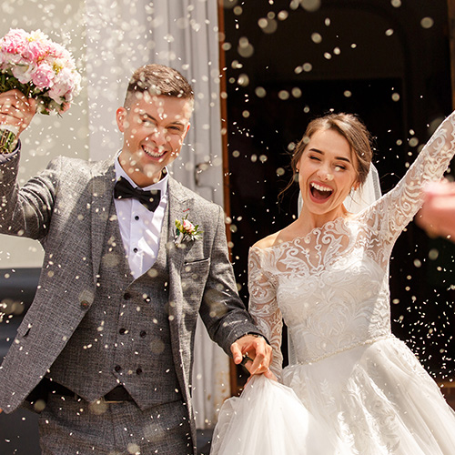 A happy newly wed couple, celebrating with confetti.