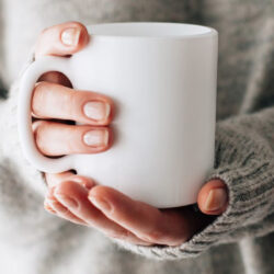 A picture of somebody holding a drink in a white mug.