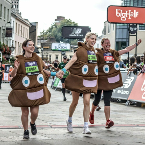 Three Big C employees crossing the finish line at the Big Half marathon in their poo emoji costumes.