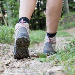 A close up of somebody who is walking through a forests' boots.