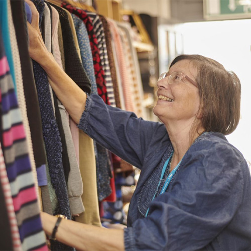 A lady smiling at a row of clothes hung up in a Big C store.