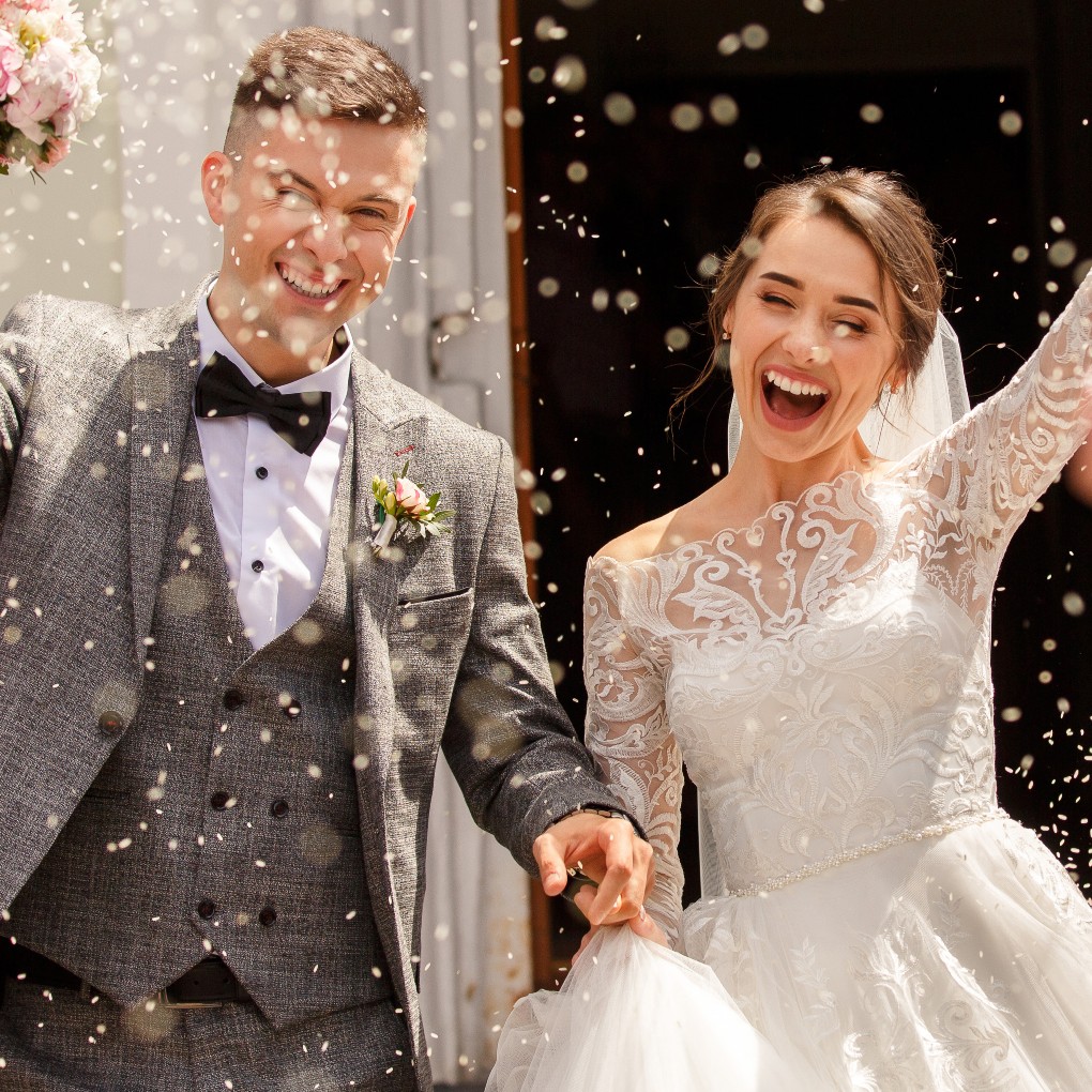 A bride and groom being covered in confetti just after getting married.