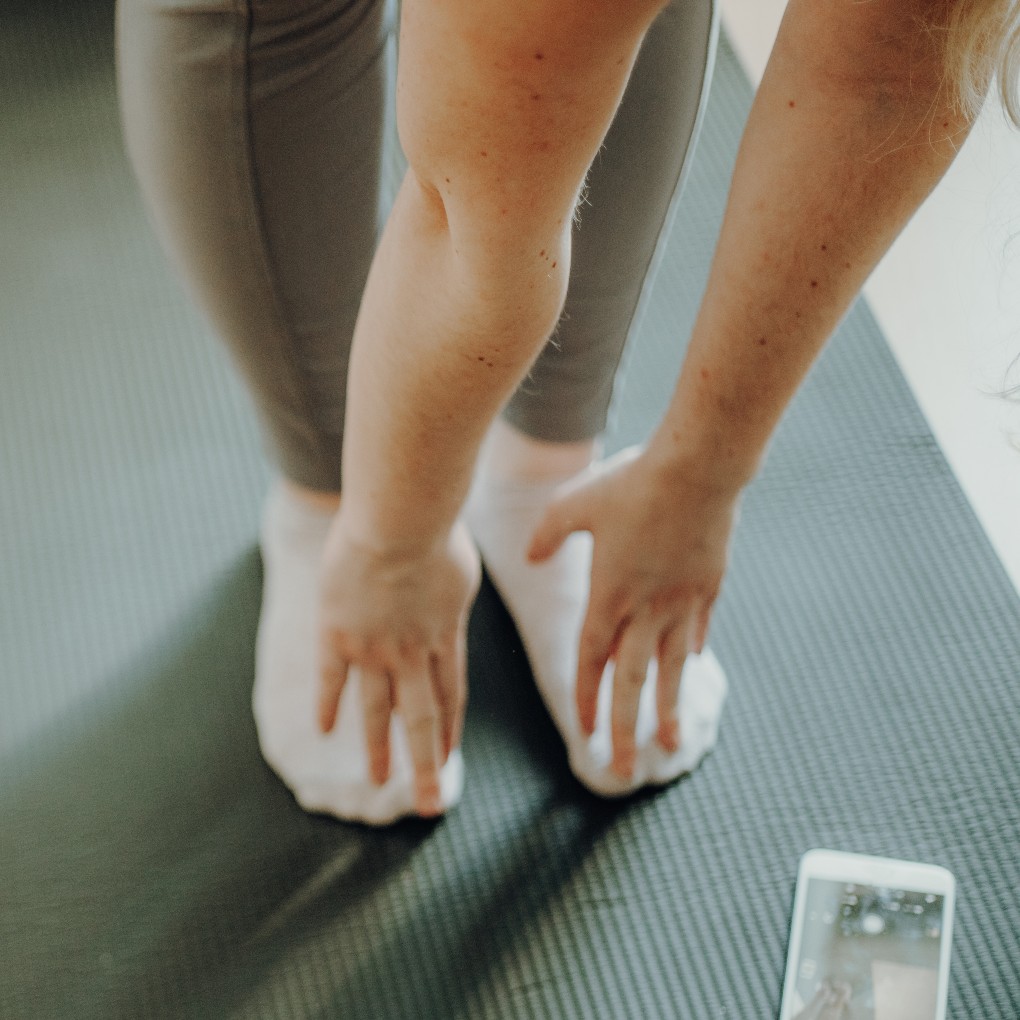 A close up on someone touching their toes to warm up for exercise.