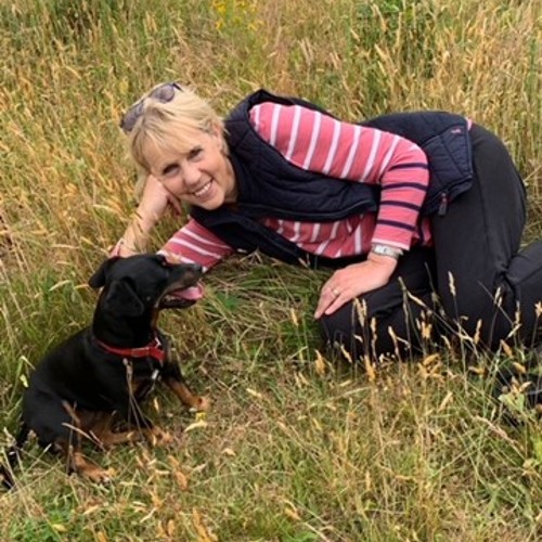 Helen, a Big C service user sitting in long grass with her dog.