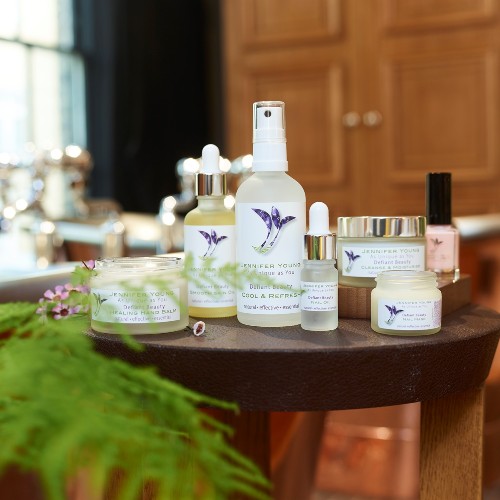 A range of Jennifer Young products on a wooden table by a plant