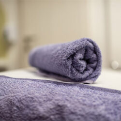 A close up of a grey towel rolled up on a therapy bed