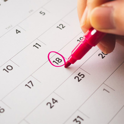A close up of someone circling a date in red pen on a calendar