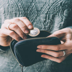A close up of a person putting a two pound coin in her purse