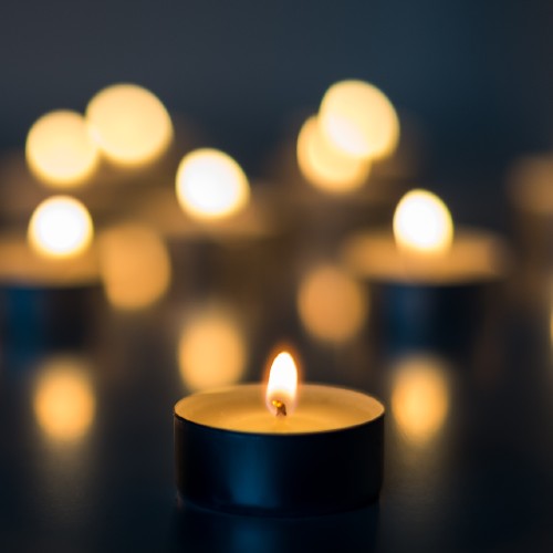 A close up of a tea light candle with other candles blurred out in the background