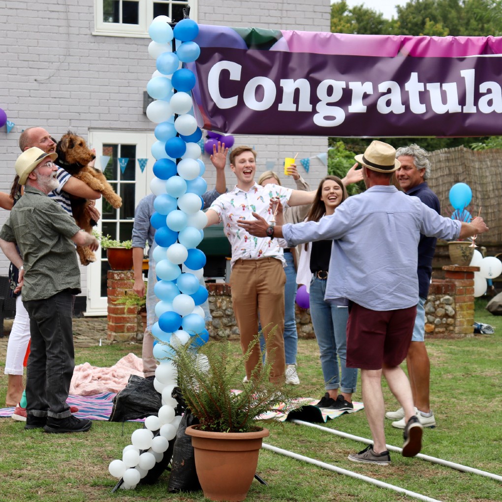 People celebrating under a congratulations banner.