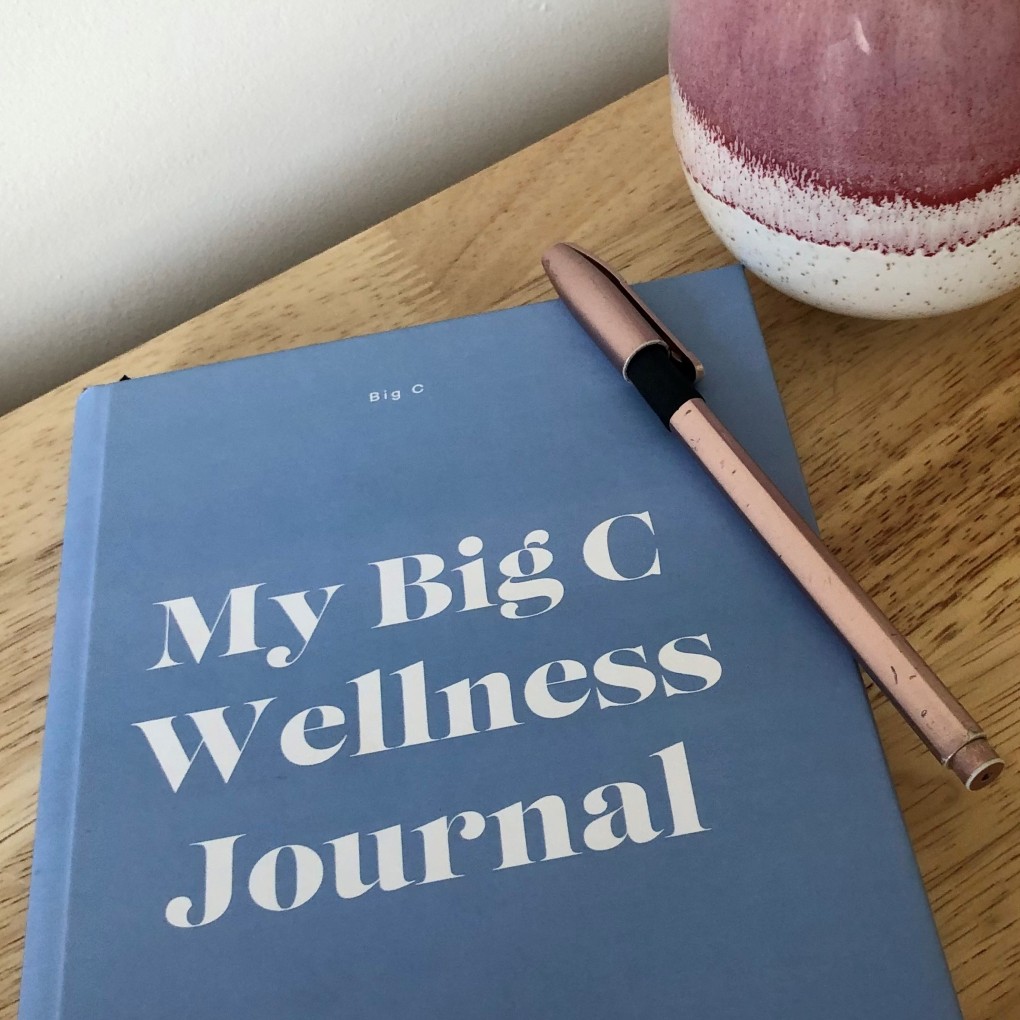 A close up of a Big C wellness journal and pen