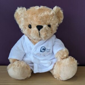 Charlie Bear, Big C's teddy bear, wearing a white dressing gown with a Big C logo on