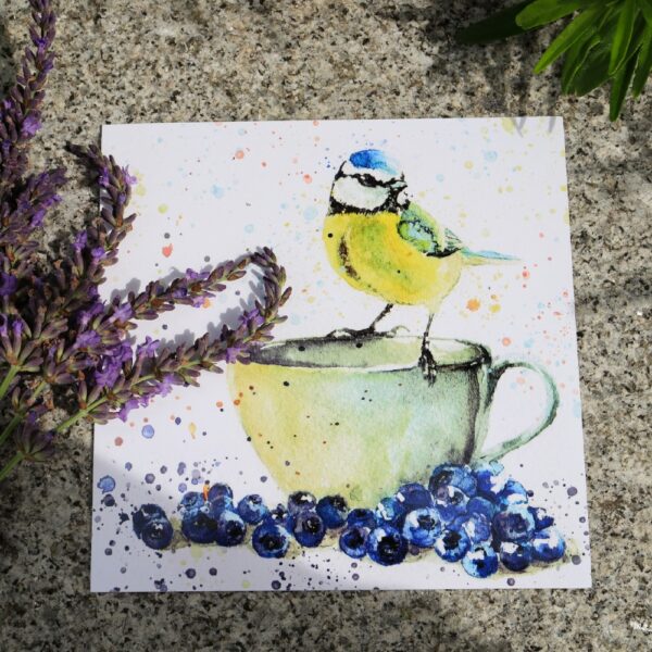A greetings card of a painted blue tit sitting on top of a tea cup, surrounded by blueberries