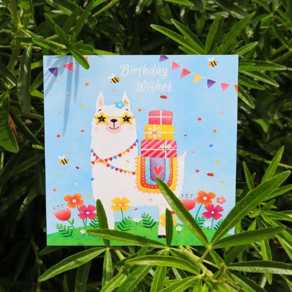 A bright greetings card of a lama with presents on its back
