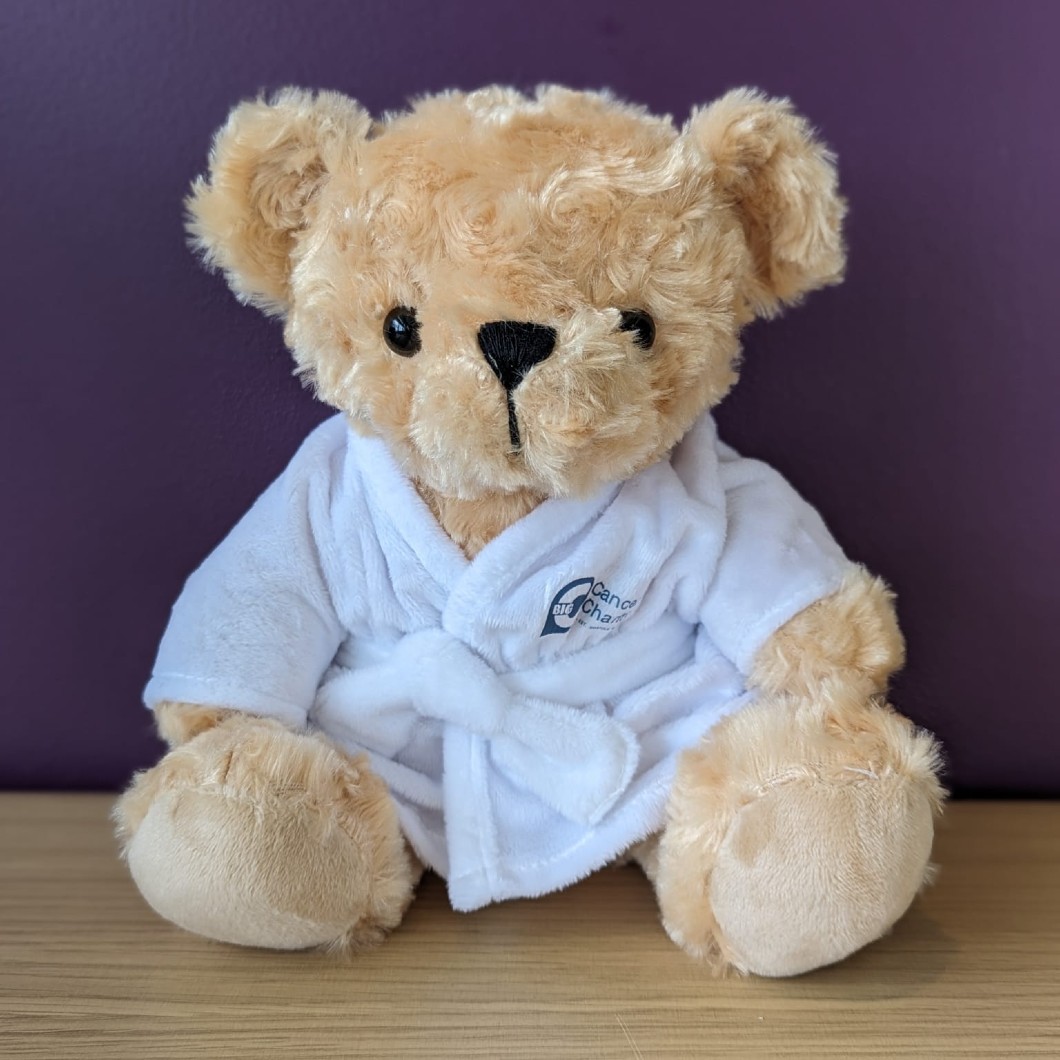 Charlie Bear, a golden teddy bear wearing a white dressing gown with the Big C logo on