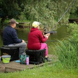 Two people sitting by a lake fishing