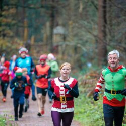 People running in a forest wearing Christmas fancy dress