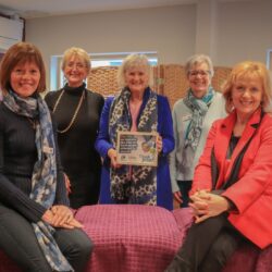 A group of the LILAC Ladies gathering around a complementary therapy bed at the Norwich City Cancer Support Centre