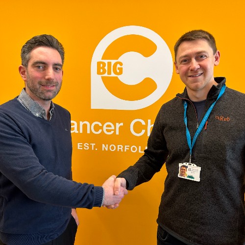 Adam Miller from ARC shaking hands with Tom Holmes from Big C with a Big C logo behind them
